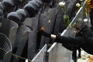 KIEV, UKRAINE: A supporter of pro-Western opposition leader Viktor Yushchenko places a flower on a riot policeman's shield as they guard the Presidential office building in Kiev, 24 November 2004. The political crisis in Ukraine deepened Wednesday as opposition leaders refused to negotiate over a disputed presidential election and their supporters entered a third day of mass street protests. AFP PHOTO / VIKTOR DRACHEV (Photo credit should read VIKTOR DRACHEV/AFP/Getty Images)