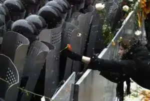 KIEV, UKRAINE: A supporter of pro-Western opposition leader Viktor Yushchenko places a flower on a riot policeman's shield as they guard the Presidential office building in Kiev, 24 November 2004. The political crisis in Ukraine deepened Wednesday as opposition leaders refused to negotiate over a disputed presidential election and their supporters entered a third day of mass street protests. AFP PHOTO / VIKTOR DRACHEV (Photo credit should read VIKTOR DRACHEV/AFP/Getty Images)